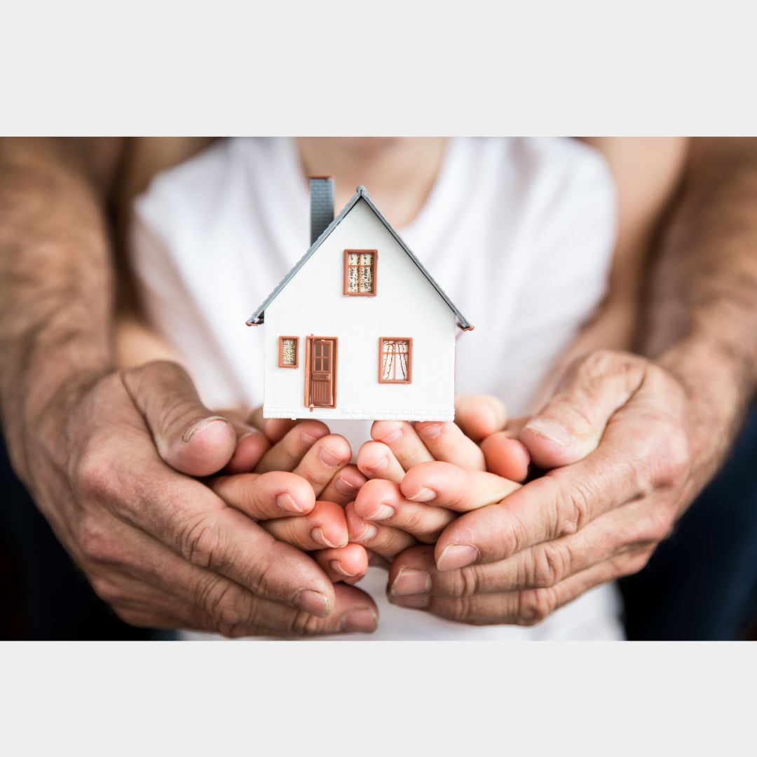 Hands hold paper cutout of a house